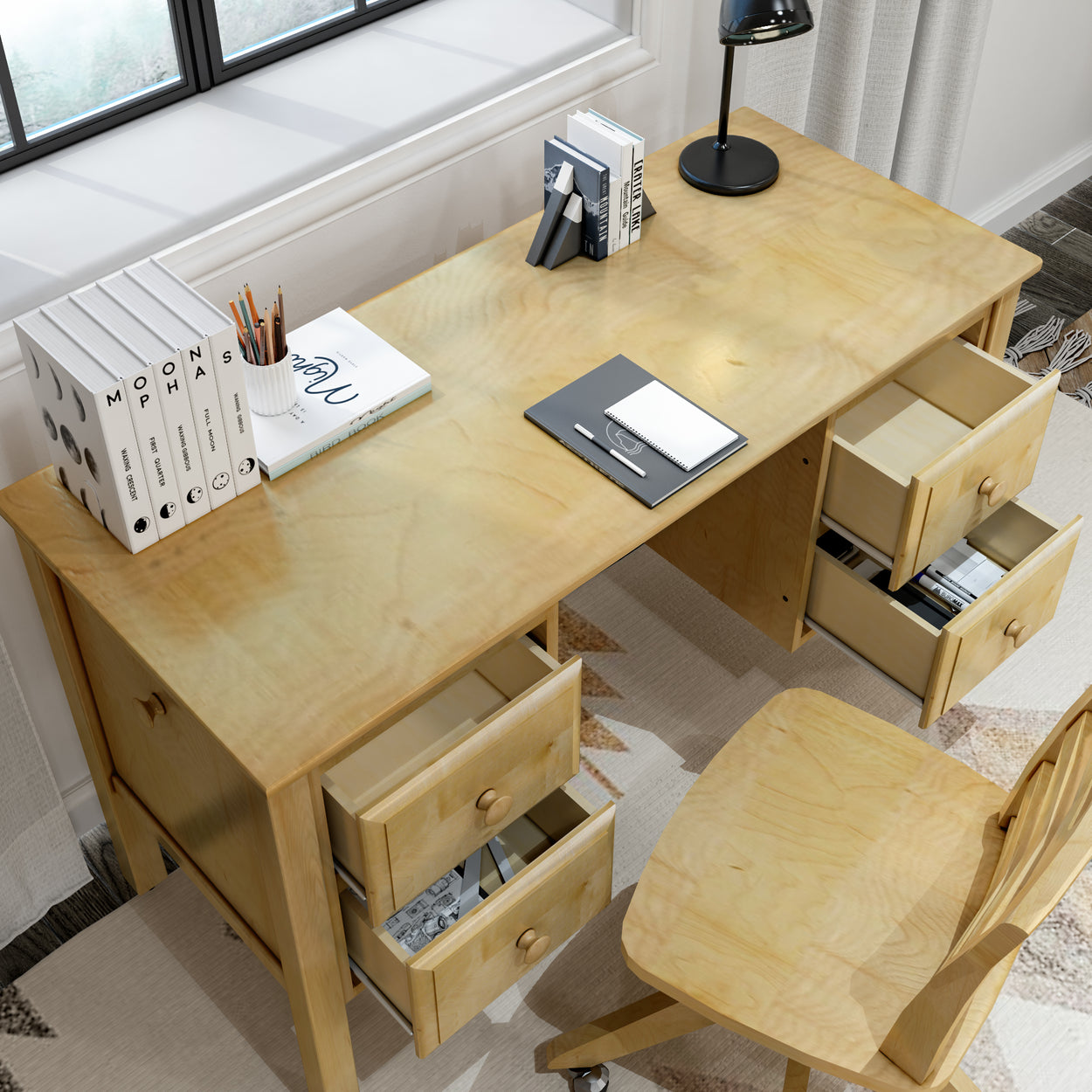 Wooden office desk with books, open drawers, and a chair in a modern home workspace.