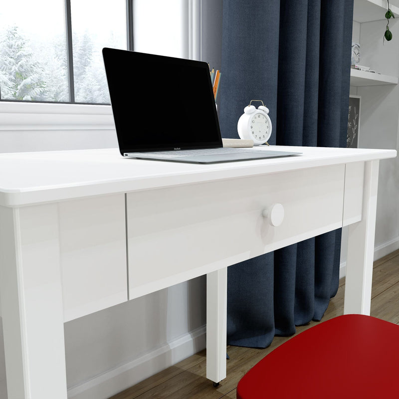 Minimal white desk with laptop, white alarm clock and pencils, red chair and navy curtains in a modern home office by a snowy window and wooden floor