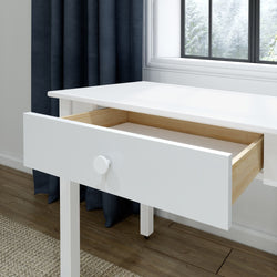 White wooden desk with an open drawer revealing natural pine interior and round knob, minimalist home office console table on hardwood floor beside a window with dark curtains