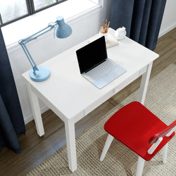 Home office workspace: small white desk with open laptop, blue desk lamp, pencil holder, white alarm clock and red chair by window
