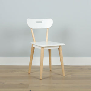 Minimalist white Scandinavian dining chair with light wood legs and handle-style cutout backrest against a pale gray wall