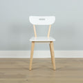 Minimalist white Scandinavian dining chair with light wood legs against a pale gray wall on a hardwood floor