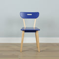 Minimalist blue chair with light wooden legs on hardwood floor against a pale blue wall