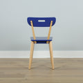 Blue wooden chair back with natural wood legs on light oak floor against a pale blue wall, minimalist interior