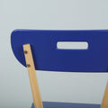 Close-up of blue modern dining chair back with rectangular cutout handle and light wood legs on pale background