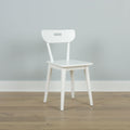 Minimal white wooden chair against a pale gray wall on light hardwood floor — Scandinavian modern interior design