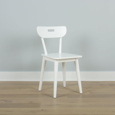 Minimal white wooden chair against a pale gray wall on light hardwood floor — Scandinavian modern interior design