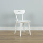 Minimal white wooden chair against a pale gray wall on light hardwood floor — Scandinavian modern interior design