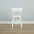 Minimal white dining chair back in a Scandinavian-style modern interior on light oak floor against a pale gray wall