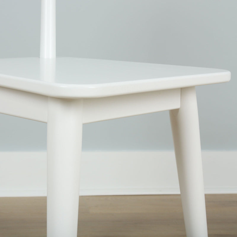 Close-up of white modern plastic stool with rounded top and cylindrical legs on light wood floor, minimalist Scandinavian design