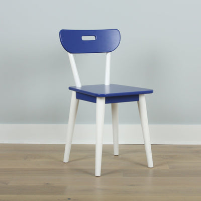 Minimalist blue chair with white legs and cutout backrest on light wood floor against pale gray wall