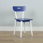 Minimalist blue chair with white legs and cutout backrest on light wood floor against pale gray wall