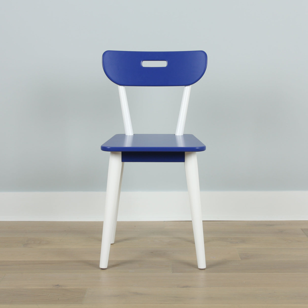 Modern blue and white wooden chair on a light wooden floor against a grey wall, minimalist interior design.