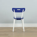 Blue and white modern dining chair back view against a light gray wall on hardwood floor, minimalist interior seating