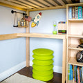 Child's room with green stool, rocket wall decor, hourglass, and bookshelves.