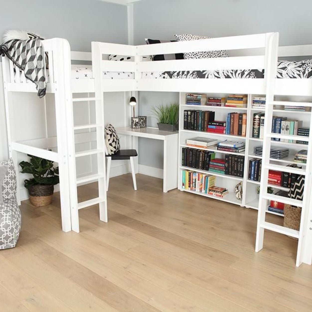 White loft bed with integrated desk and bookshelves in a modern, minimalist room featuring wooden flooring and decorative plants.