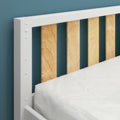 Close-up of modern white-framed wooden slatted headboard against teal wall with white bedding — minimalist bedroom design
