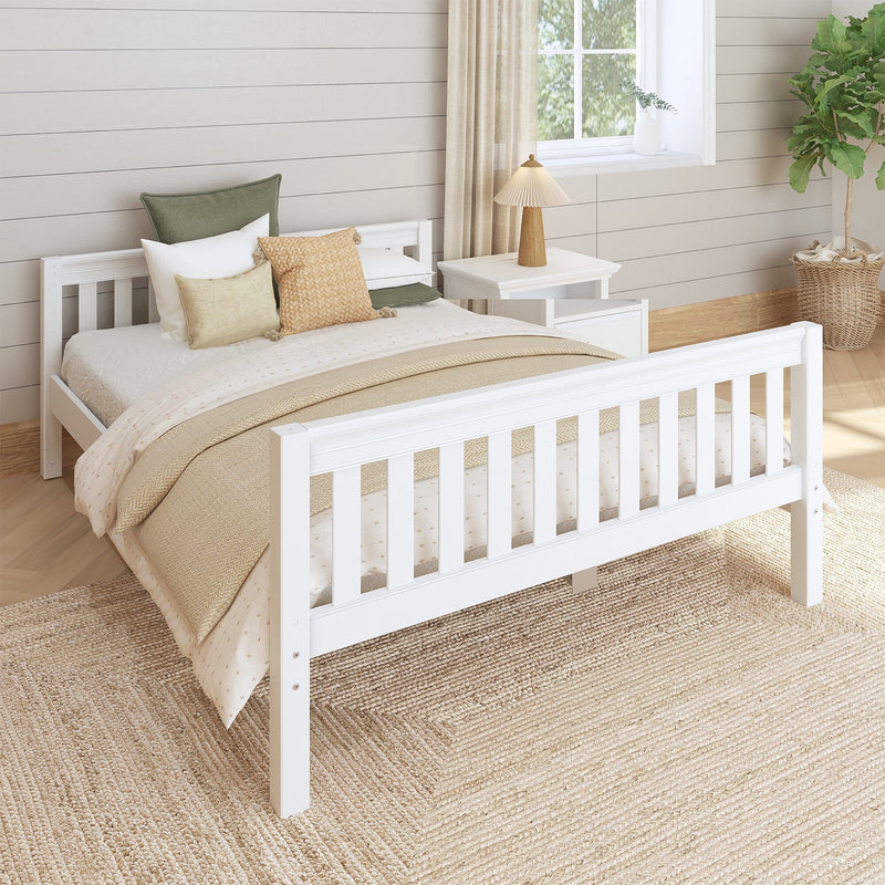 Cozy neutral farmhouse bedroom with white wooden bed, layered beige bedding, textured woven pillows, jute rug, wooden bedside lamp and potted fiddle‑leaf fig by a sunlit window