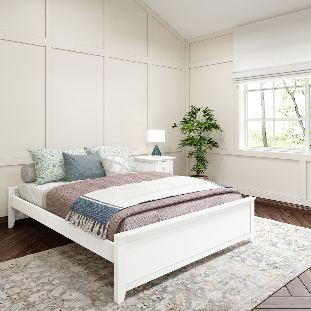 Modern bedroom interior with white bed and cozy pillows, featuring a bedside table and green plant by a window with natural light.