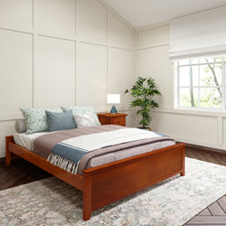 Cozy bedroom with modern wooden bed, layered bedding, floral pillows, elegant nightstand, indoor plant, and large window letting in natural light.