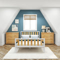 Nursery with teal accent wall and sloped ceiling, white-framed window, wooden crib and matching dressers, bedside lamp and framed art