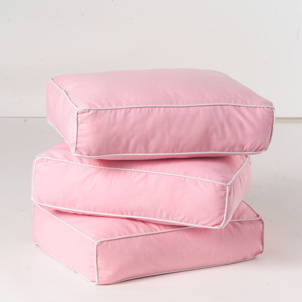 Pink floor cushions stacked, highlighting soft fabric texture and comfortable design for home decor.