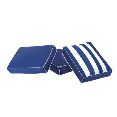 Set of three navy blue square patio cushions with white piping, two solid and one blue-and-white striped, for outdoor seating