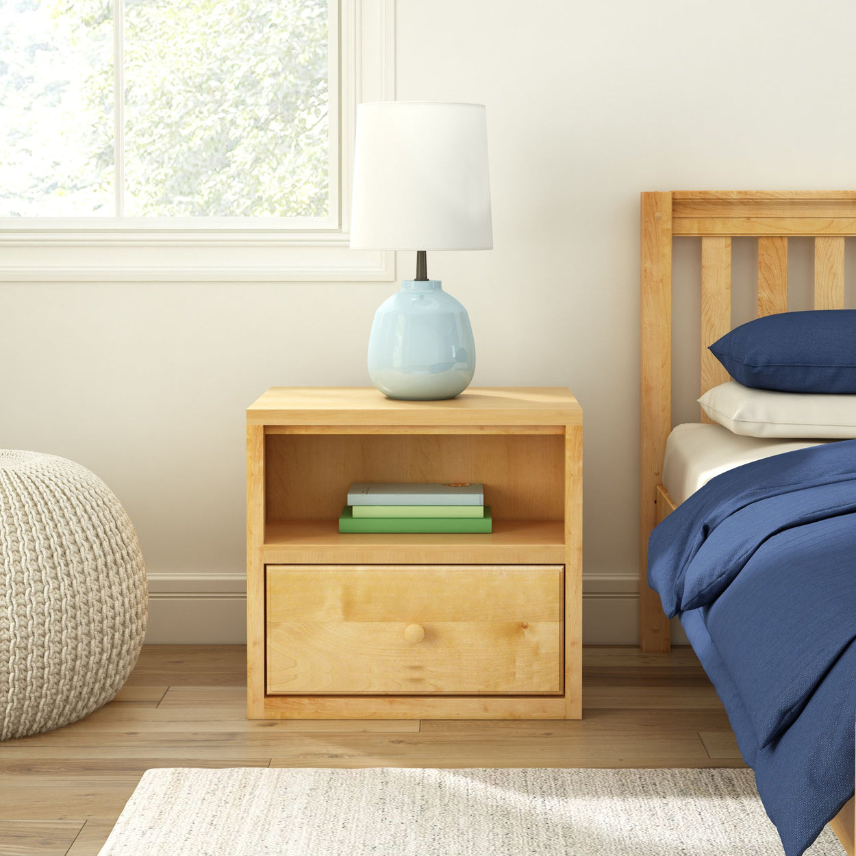 Bedroom with wooden nightstand, modern lamp, and cozy bedding in bright, airy space.