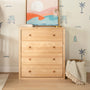 Light wood dresser with coastal abstract print, brass table lamp, beach-themed wall decals and woven basket with fringed throw blanket