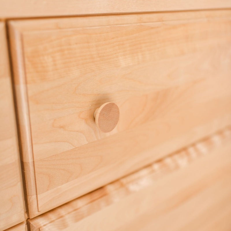Close-up of light wood dresser drawer with round wooden knob, natural wood grain texture and minimalist bedroom furniture detail