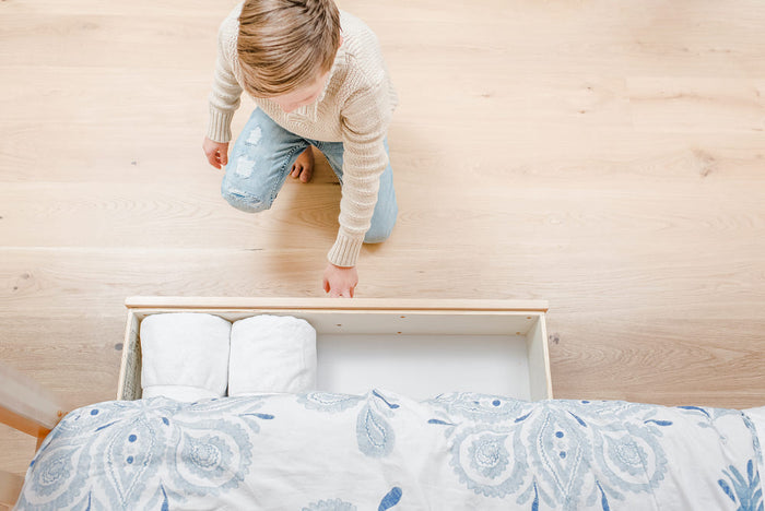 Child playing with a bed in a minimalistic room.
