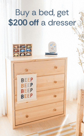 Natural wood four-drawer children's dresser with toy cars and sign saying "Buy a bed, get $200 off a dresser" — nursery dresser sale, affordable kids' bedroom furniture