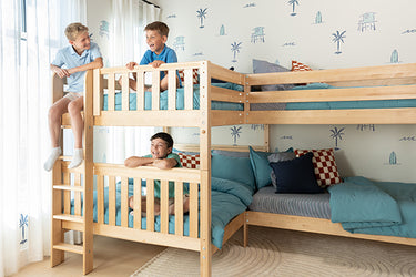 Three boys on light-wood bunk beds with teal bedding in a coastal-themed shared children's bedroom, space-saving kids' bunk beds