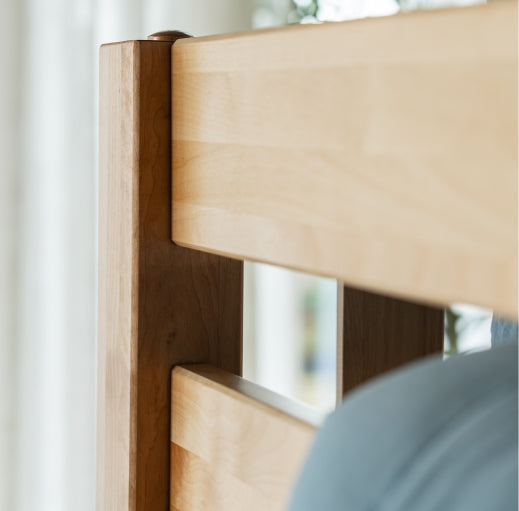 Close-up of a wooden headboard with a blurred background.
