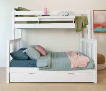 White wooden bunk bed with trundle drawer and built-in storage stairs, navy bedding and plush toy in bright modern kids' bedroom