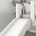 White wooden indoor slide attached to a bunk bed with blush pink mattress and textured pillow, modern kids bedroom decor with greenery
