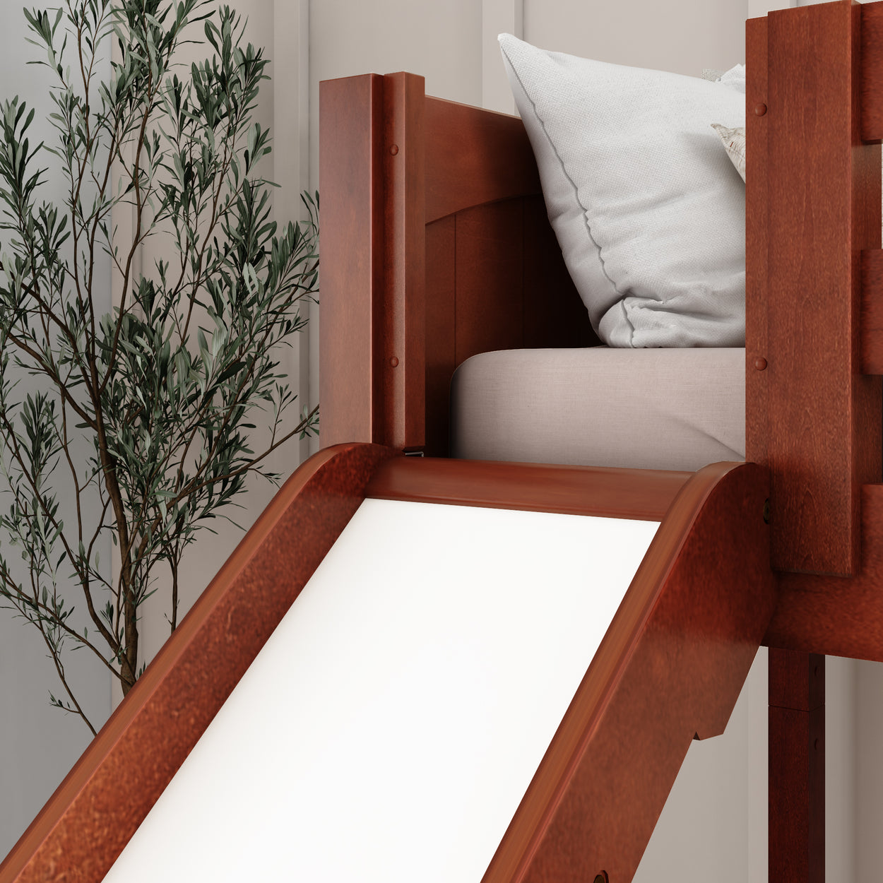 Wooden loft bed with built-in slide and cozy bedding next to a decorative plant in modern bedroom.