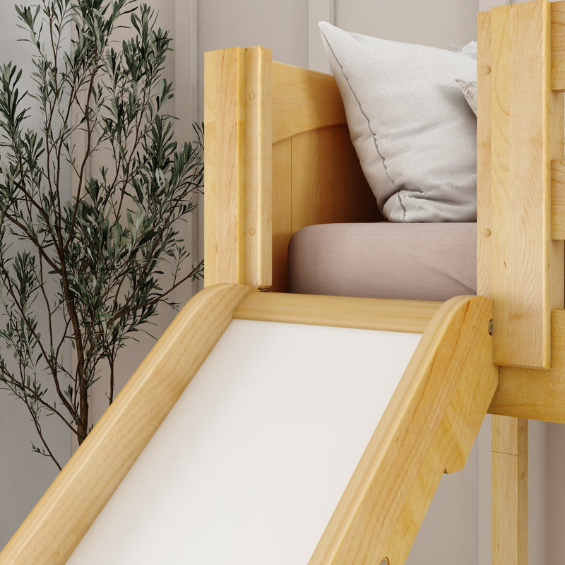 Close-up of a natural wood children's slide attached to a bed with neutral pillows and an indoor plant in a modern nursery