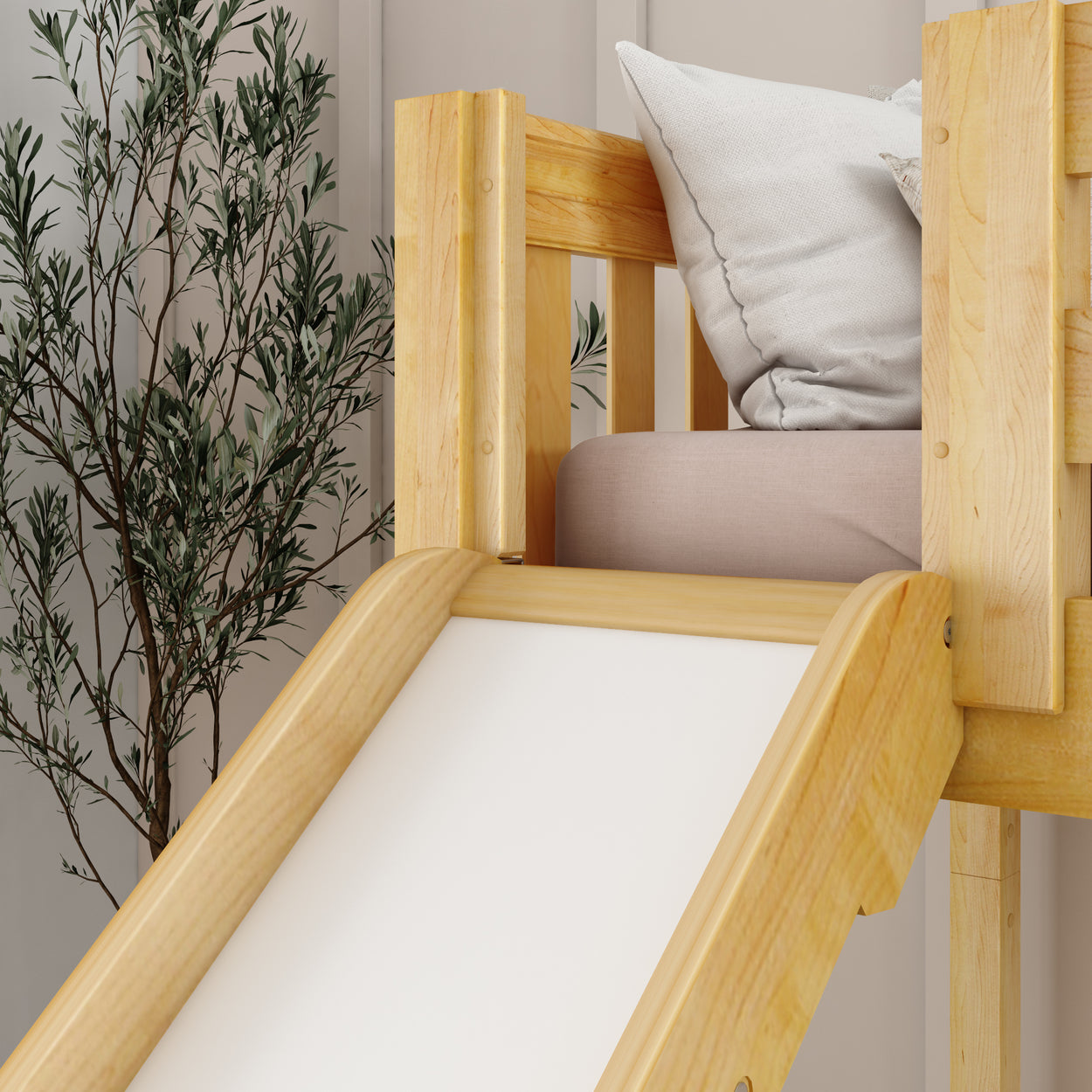 Wooden indoor loft bed with a slide and large cushions next to a potted plant.