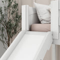 Close-up white indoor children's bed slide attached to a white wooden bunk with blush mattress, textured pillow and decorative plant