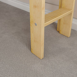 Light wood chair leg resting on textured gray carpet flooring.