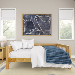 Cozy minimalist bedroom with modern art, featuring a wooden daybed, blue knitted blanket, and neutral decor.