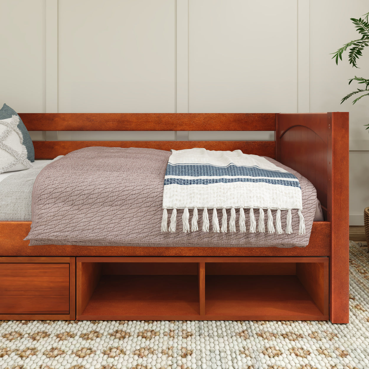 Daybed with storage drawers, cozy blankets, and decorative pillows in a stylish bedroom setup.