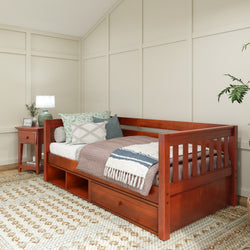 Wooden daybed with storage drawers in a cozy bedroom setting, featuring a side table and decorative pillows.