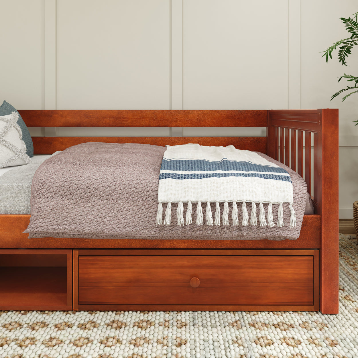 Stylish wooden daybed with a cozy blanket and pillows, featuring storage drawers underneath, perfect for a modern bedroom.