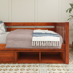 Wooden daybed with storage drawers and cozy bedding in a minimalist bedroom setting.