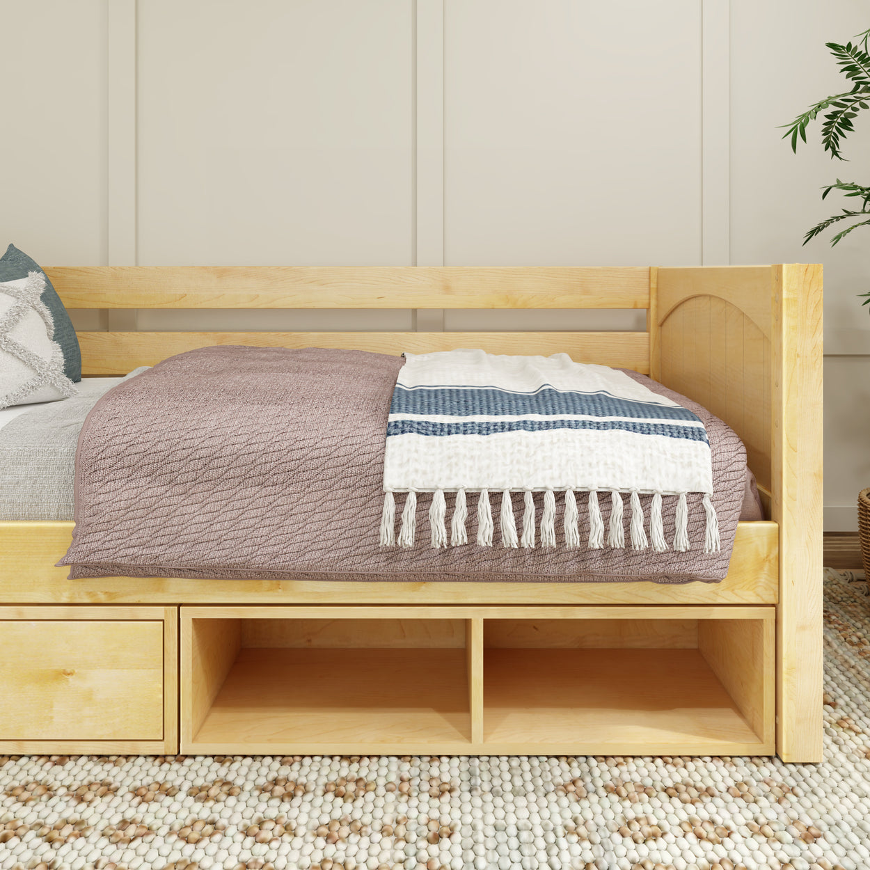 Wooden daybed with drawers and cozy blankets in a modern bedroom setting.
