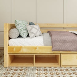 Cozy modern daybed with wooden frame, decorative pillows, and knitted throw blanket on textured carpet in light-filled bedroom.