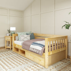Cozy bedroom with a wooden daybed featuring colorful pillows and a woven blanket, next to a wooden nightstand with a lamp and decorative plant.