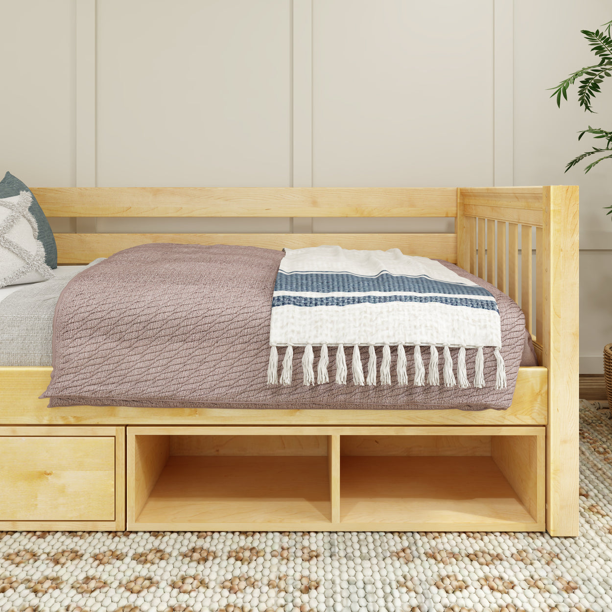 Natural wood daybed with storage drawers, adorned with a cozy blanket and decorative throw pillows, perfect for a modern bedroom.